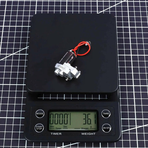 Upgraded 55T Carbon Brush 050 Motor With Aluminum Center Gear Case on digital scale showing weight for Axial SCX24 vehicles.