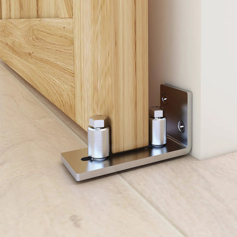 Close-up of wall-mounted stainless steel barn door floor guide set, flush bottom design, installed on light wood floor; Barn Door Floor Guide Set Of 2, Stainless Steel Adjustable Wall Mounted Floor Guide For Doors Up To Two And One Eighth Inches Thick, Flush Bottom Design For Floor Friendly Finish, Smooth And Quiet Roller Operation, Super Easy Install.