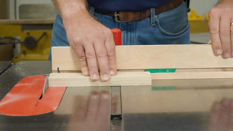 Person using table saw with dovetail track stop, part of MicroJig MatchFit Pop Stop 6-Pack for woodworking, demonstrating usage on sled.