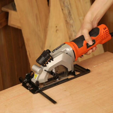 Powerful 4 Amp Mini Circular Saw with Laser Guide and Vacuum Adapter being used on wood, showing compact design and control handle.
