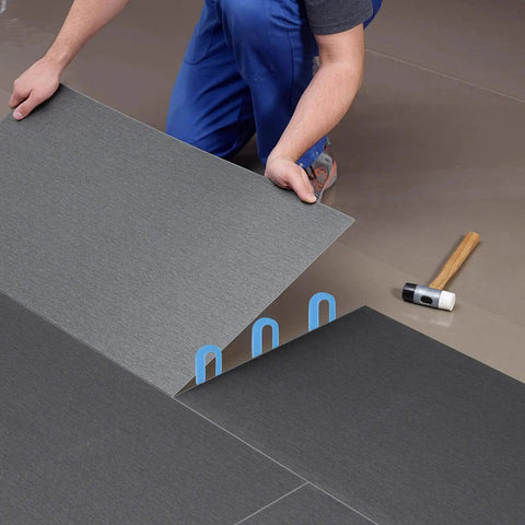 Installer using Horseshoe Shims Kit Color Coded U Shaped Plastic Leveling Shims 2x1.3in for tile leveling with rubber mallet nearby