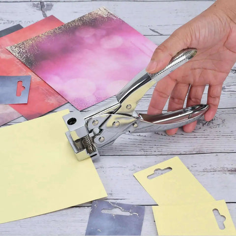Hand using Heavy Duty T Slot Hole Punch Handheld Tool for ID cards, punching hole in yellow cardstock, silver zinc alloy, spring action.