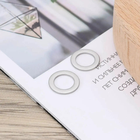 30Pcs Flat Washers 304 Stainless Steel 10x16x1mm Door Hinge Gaskets on a wooden table with a magazine