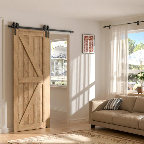 Wooden sliding barn door installed on a track in a sunlit living room next to a sofa and window with curtains.