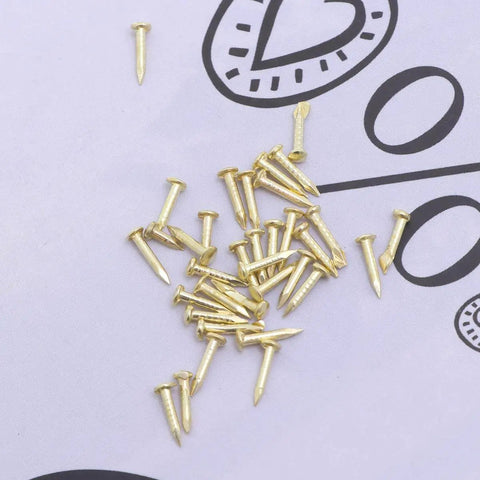 Mini Brass Cabinet Hinges For 1 To 12 Dollhouse Furniture With 48 Screws, shown are small brass screws on a paper background.