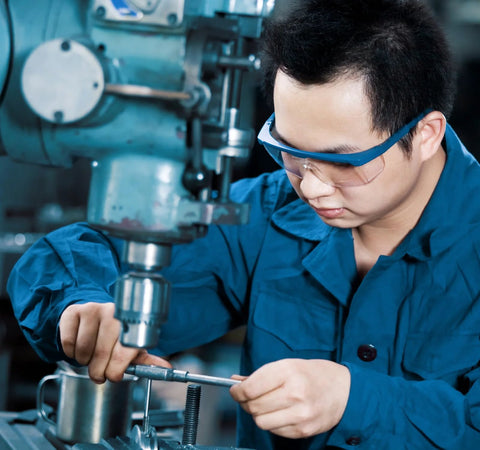 Donepart R12-2RS ball bearings being handled by a technician in blue safety gear at a machining station.