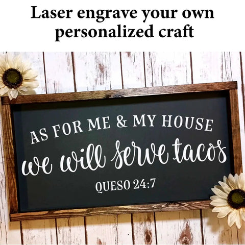 Engraved black sign with 'As for Me & My House, We Will Serve Tacos' and 'Queso 24:7' surrounded by wooden frame and flowers.