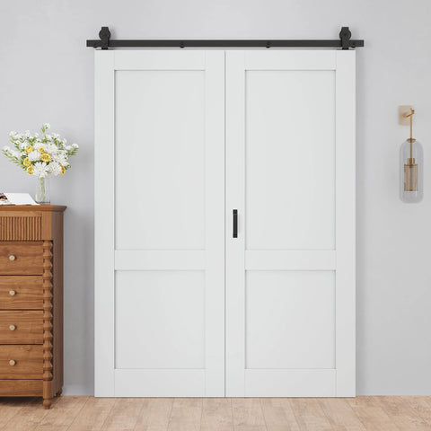 48 By 80 Inch Bifold Barn Door With 64 Inch Track Hardware Two Lite White Primed MDF Panels One And Three Eighths Inch Thick Solid Core Sound Insulated Pre Drilled Space Saving Sliding Door For Laundry Room Or Bedroom displayed installed against a white wall with wooden furniture beside