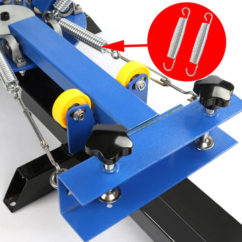 Two bociloy extended tension springs with hooks, steel coil, mounted on blue machinery frame.