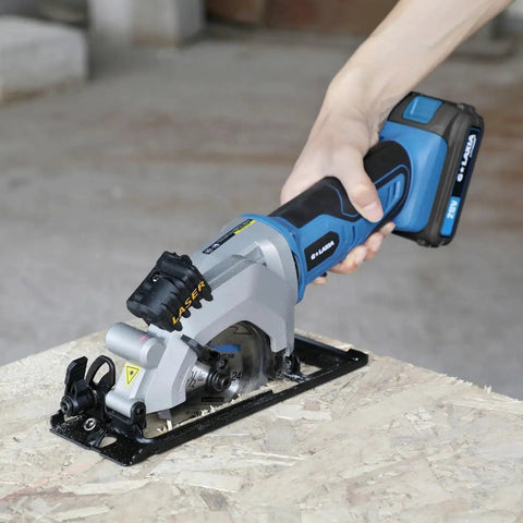 Person using Pro Grade Mini Cordless Circular Saw With Laser Guide And Rip Guide For Precise DIY Cuts, 4-1/2 Inch Blade, 3400 RPM No-Load, Includes 24T And 60T High Quality Blades, Max Cutting Depth 1-11/16 At 90 Degrees And 1-1/8 At 45 Degrees, Blue on wood surface