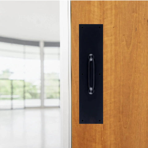 Commercial 15 Inch Stainless Steel Pull Door Plate In Matte Black Finish mounted on a wooden door in an industrial setting.