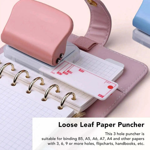 Pink handheld 3-hole paper punch for binders and notebooks punches up to five pages at once with clean 5.5mm holes, shown with notebook
