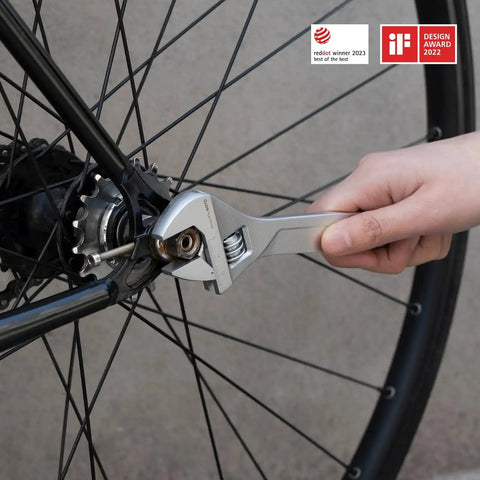 Hand using wrench on bike wheel, showcasing practical use of 18 Piece Electric Screwdriver Tool Kit With LED Light 3 Torque Settings 10 Bits
