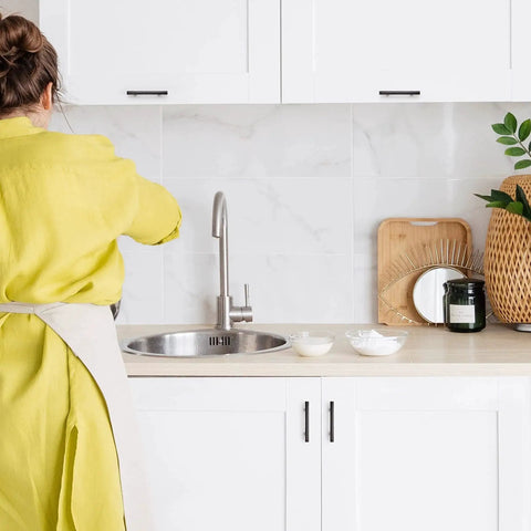 Person in yellow reaches over sink with Oil Rubbed Bronze Curved Cabinet Handles Arch Drawer Pulls visible on white cabinets.