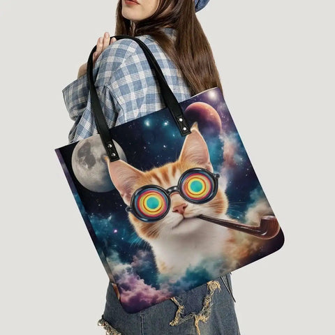 Woman carrying a tote bag featuring a cat wearing rainbow glasses and a pipe, with a space background including the moon.