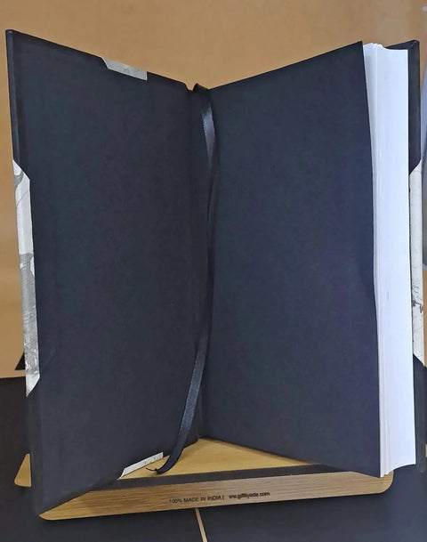 Leather-bound book in dark blue, opened with a ribbon bookmark and blank white pages visible.