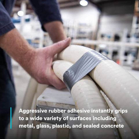 Person using Heavy Duty Duct Tape DT11 Silver 48 mm x 54.8 m (11 mil) on pipes, demonstrating aggressive rubber adhesive.