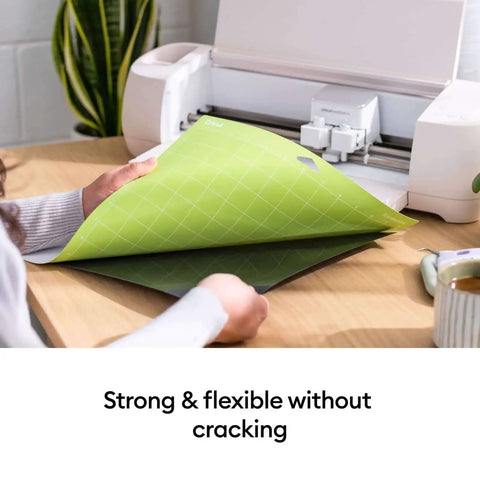 Person holding StandardGrip 12x12 Cutting Mat Pack for Explore and Maker Machines, showing flexibility and strong adhesive.