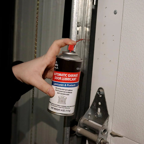 Hand using 4 oz aerosol Garage Door Lubricant Spray for Real Smooth Operation Quiet Squeaks and Reduce Friction on Tracks Hinges and Rollers