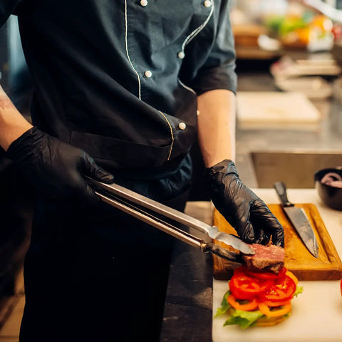 Chef wearing Black Vinyl Disposable Exam Gloves 4 Mil Latex Free Powder Free Medical 1000 preparing food in kitchen