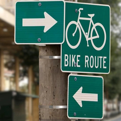 Green bike route sign and arrows on a post, secured with Center Punch Clamp Five Eighths Inch Wide 0.025 Inch Thick Five Inch Diameter 201 Stainless Steel Box Of 25 High Strength Corrosion Resistant Clamp For General Maintenance And Emergency Field Repairs.