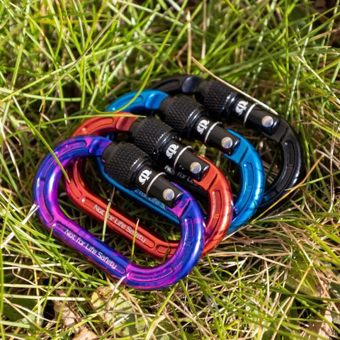 Colorful set of mini aluminum keylock screw-lok carabiners for throwline setup and gear mounting, showing reinforced frames on grass.