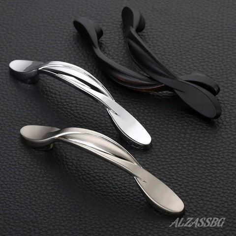 Three twisted arch cabinet pulls in brushed satin nickel, silver, and black on textured surface, showing design for 10 Pack Brushed Satin Nickel Cabinet Pulls With 3 Inch Hole Centers Arch Twisted Design For Cabinets And Drawers Kitchen Furniture Hardware AL3027SN High Quality Solid Construction For Everyday Use.