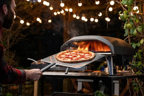 16 Inch Metal Pizza Peel For Ovens, Lightweight Aluminum Pizza Paddle With Long Handle, Rectangle Pizza Turner For Easy Pizza Turning And Serving, Perfect Pizza Oven Accessory And Tools By Ooni in use on outdoor pizza oven