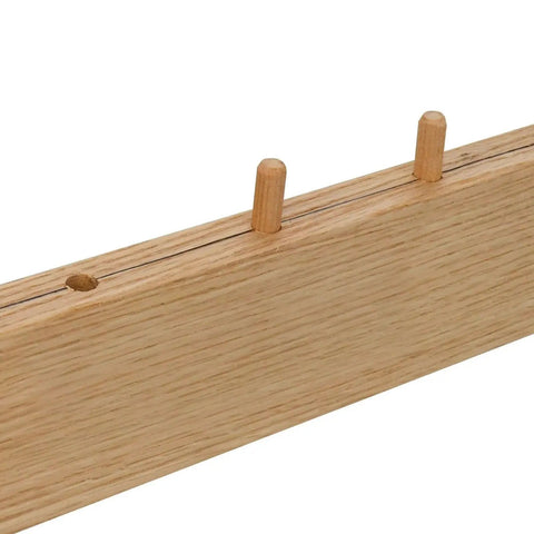 Wooden dowels lined up on an oak board showing alignment and assembly use, illustrating woodworking joints.