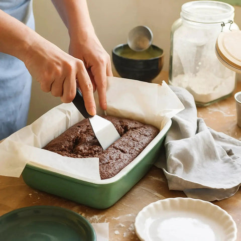 10 Piece Mini Stainless Steel Spatula Set With Five Solid And Five Slotted Spatulas For Kitchen Cooking And Serving Perfect For Pancakes Eggs Cookies Brownies Desserts Lasagna And More being used to cut a dessert in a green tray