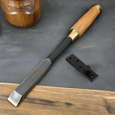 Wood chisel with wooden handle and black metal door latch set on a wooden and gray background