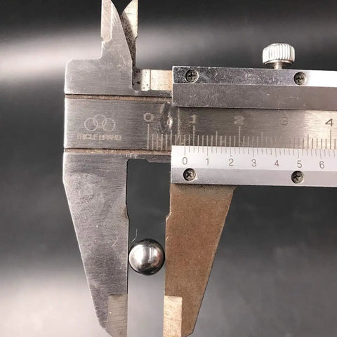 Caliper gauge measuring a metal strip; knurled thumb screw and metric and inch scales visible.