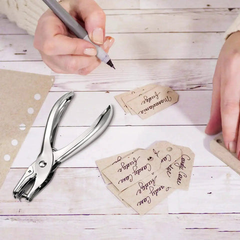 24 Pack 1/4 Inch Single Hole Punch Set Metal Paper Puncher With 5 Sheet Capacity silver finish shown next to handwritten tags on a desk