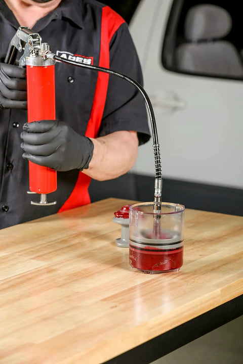 Mechanic using Two Piece Deluxe And Standard Bearing Packer Kit for quick flushing of old grease and easy repacking of wheel bearings.