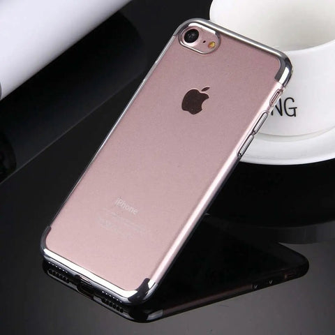 A smartphone with a transparent protective case on a black surface beside a white cup.