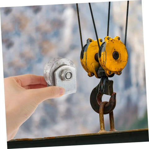 Hand holding Industrial Cast Iron Groove Wheel Garage Door Roller For Caster Bracket in front of yellow hoist, showcasing size and design.