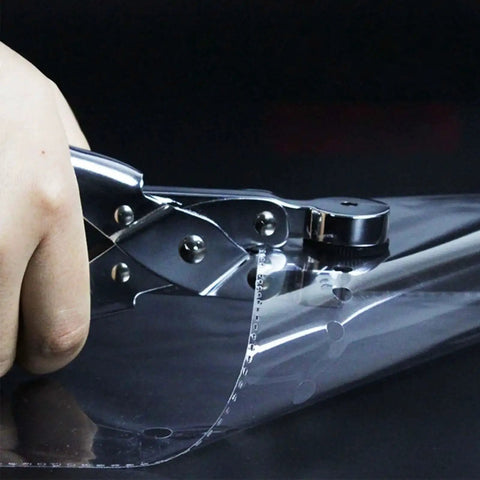 Handheld Single Hole Paper Punch For Scrapbooking And Office Use, shown punching clear plastic film with a metal body