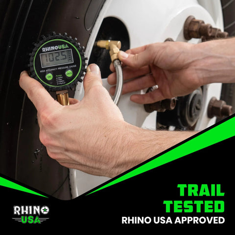 Close-up of Rhino USA digital tire pressure gauge with glow dial and braided hose attached to a car tire valve