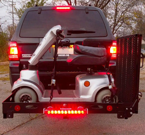 Rear view of hitch-mounted cargo carrier with LED tail lights carrying a mobility scooter on a SUV