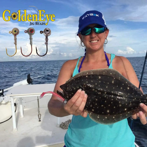 Woman on boat holding flounder with GoldenEye Jig Heads displaying inshore jig head for soft plastics with red eye and red hook.