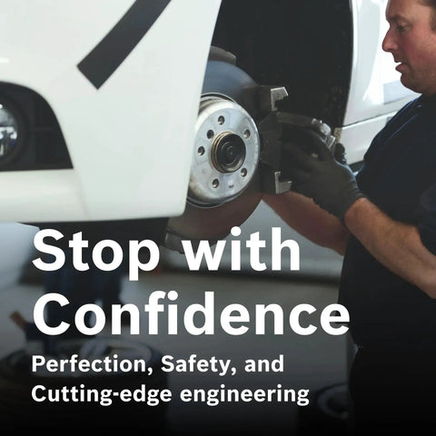 Front brake rotor and caliper assembly on a white vehicle being serviced by a mechanic wearing gloves.