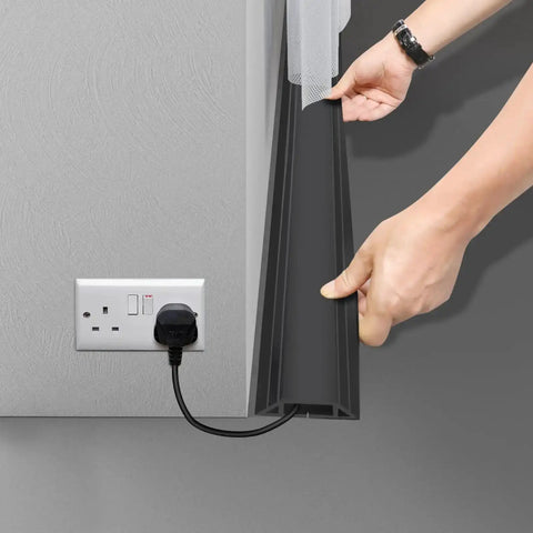 Person installing Heavy Duty PVC Floor Cord Cover For Wires And Cables, Easy Unroll Floor Cable Management Ramp, Black, on floor near outlet.