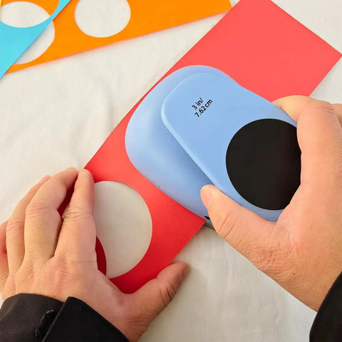 Using the XL 3 Inch Circle Punch For Paper Crafts And Scrapbooking Easy To Use Spring Action Lever Cutter, blue, to cut red paper.