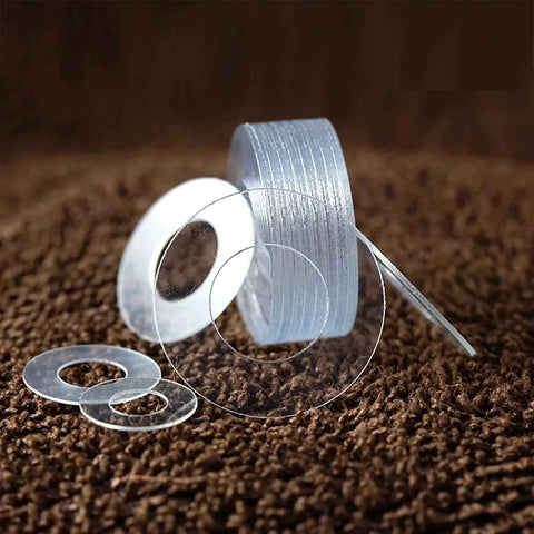 Stack of transparent PVC hard washers in various sizes from M1.2 to M20 for screw insulation and vibration isolation applications.