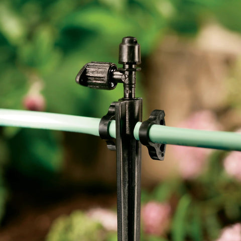 Orbit 67710 black 1/4-inch tubing high-pressure clamp securing green irrigation tubing to an upright stand
