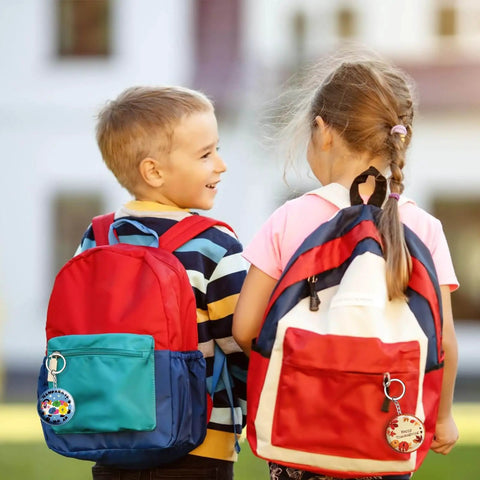 Two children with colorful backpacks featuring button badges from Epic 100 Pack Button Maker Kit For DIY Badges 2.25 Inch Metal Shells.