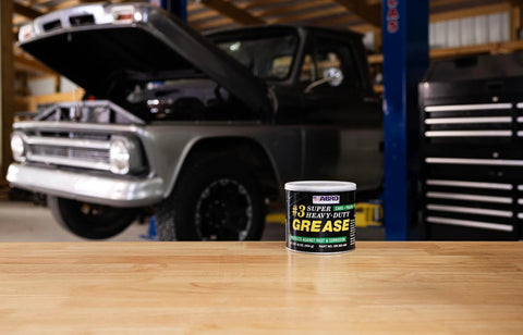 Masters Heavy-Duty No. 3 Wheel Bearing Grease, 16 oz can on workbench in garage with raised truck in background