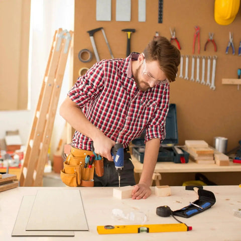 Person in workshop drilling into wood with tools in background