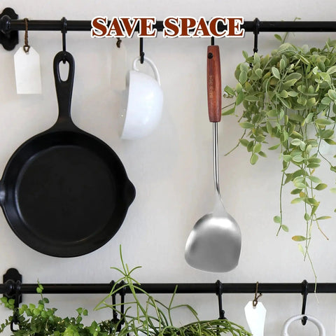 Stainless Steel Wok Spatula With Wooden Handle, 14.17 Inch Long Wok Tool hanging on kitchen rail next to pan and plants.