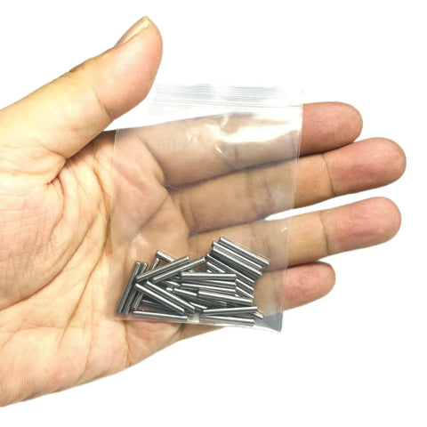Hand holding a small plastic bag containing a set of 3/32 x 3/4 metal dowel pins, part of the Three Thirty Second Inch By Three Quarter Inch Dowel Pins Set Of Thirty Metal Dowel Pins Shelf Pegs For Shelves Supports Bearings Alloy Steel Wood Bunk Bed Pegs For Furniture Repair.